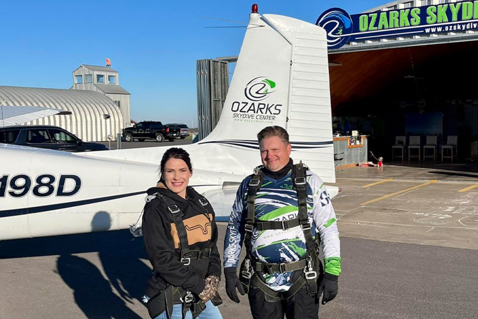 young woman smiles with instructor before boarding skydiving aircraft